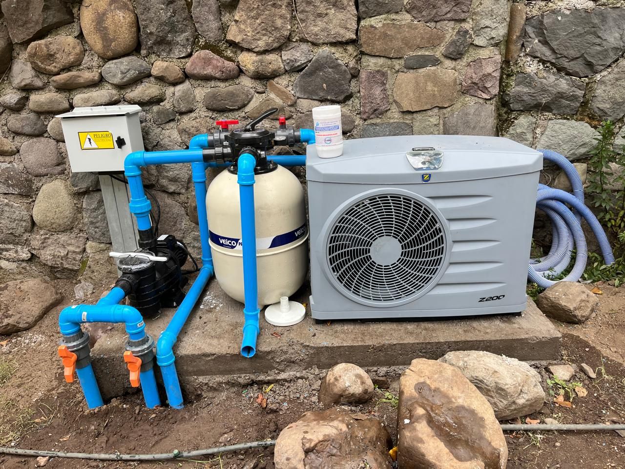 Bomba de calor instalada junto al filtro y al motor de una piscina