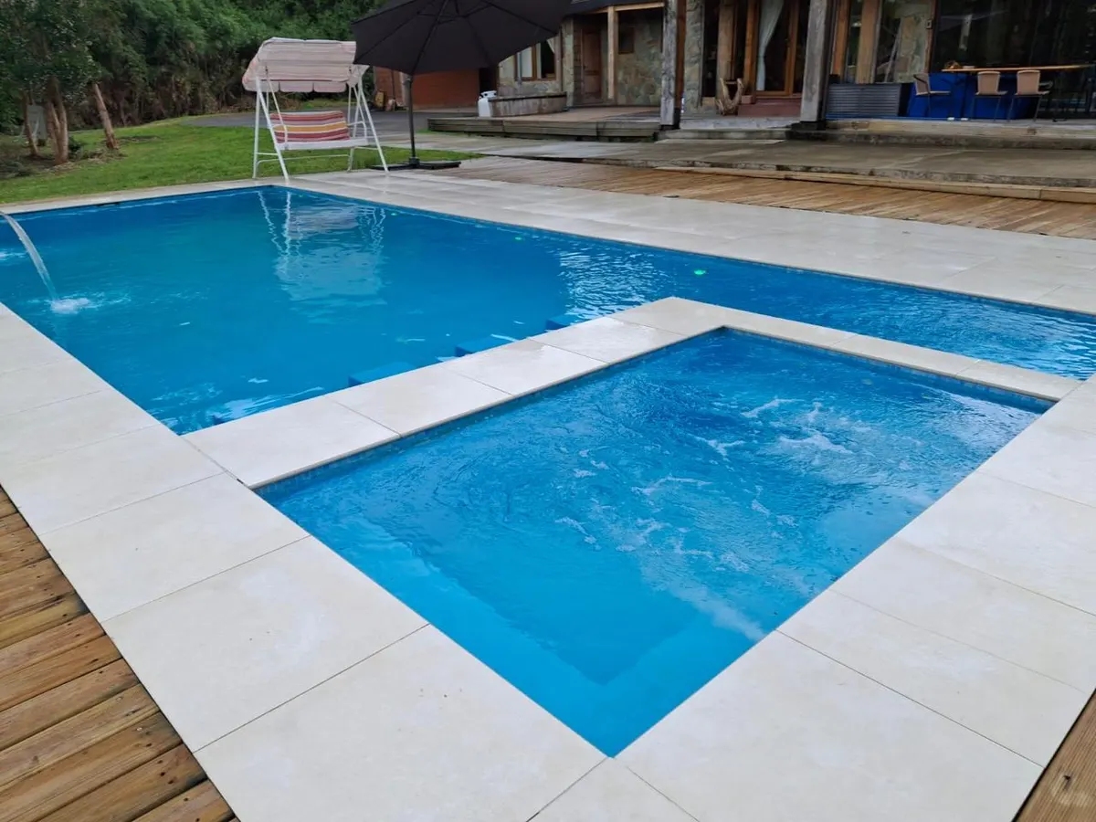 Piscina de hormigón terminada, con playa de poca profundidad y terraza de madera