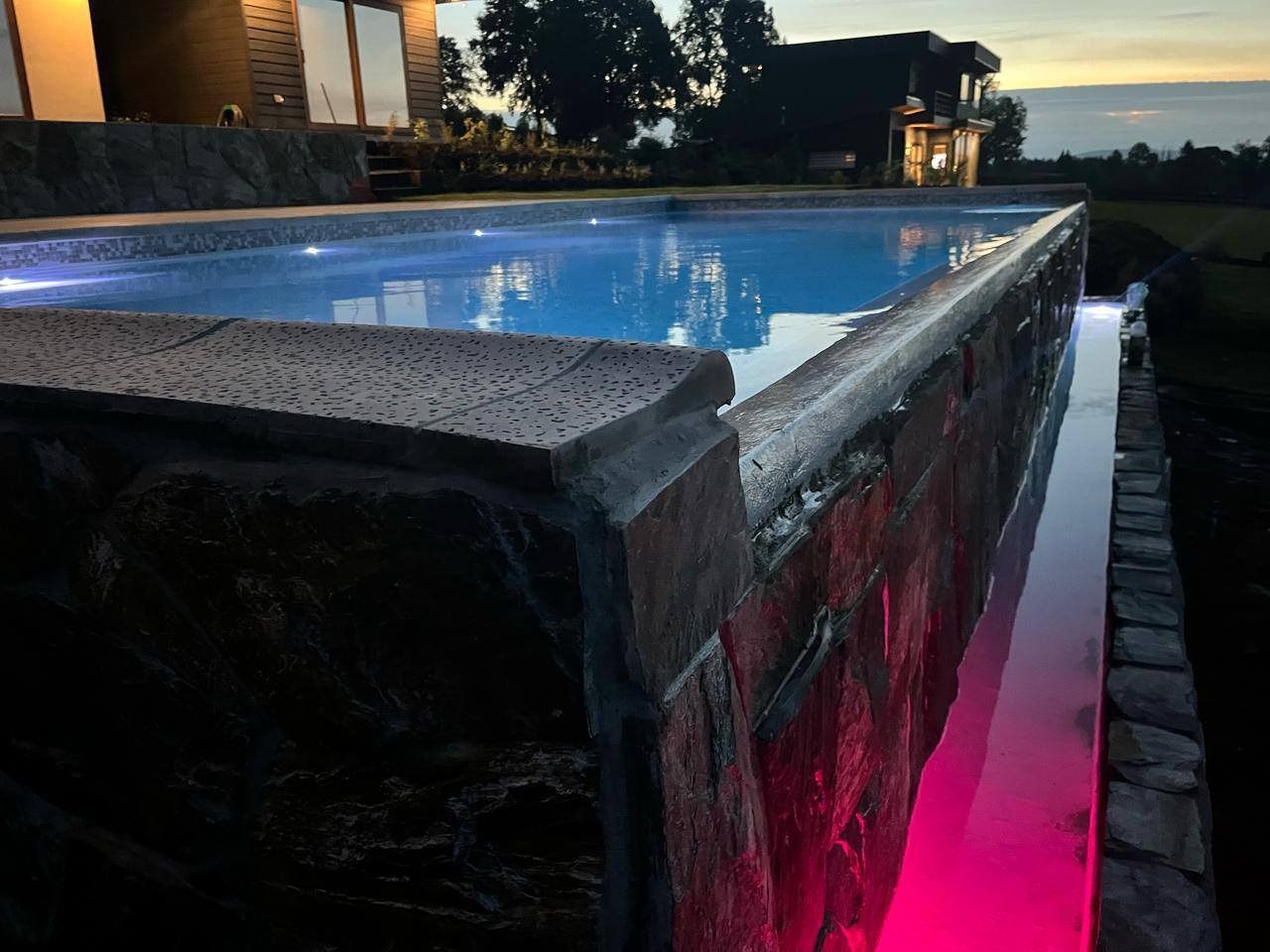 Piscina con borde de piedra e iluminación nocturna