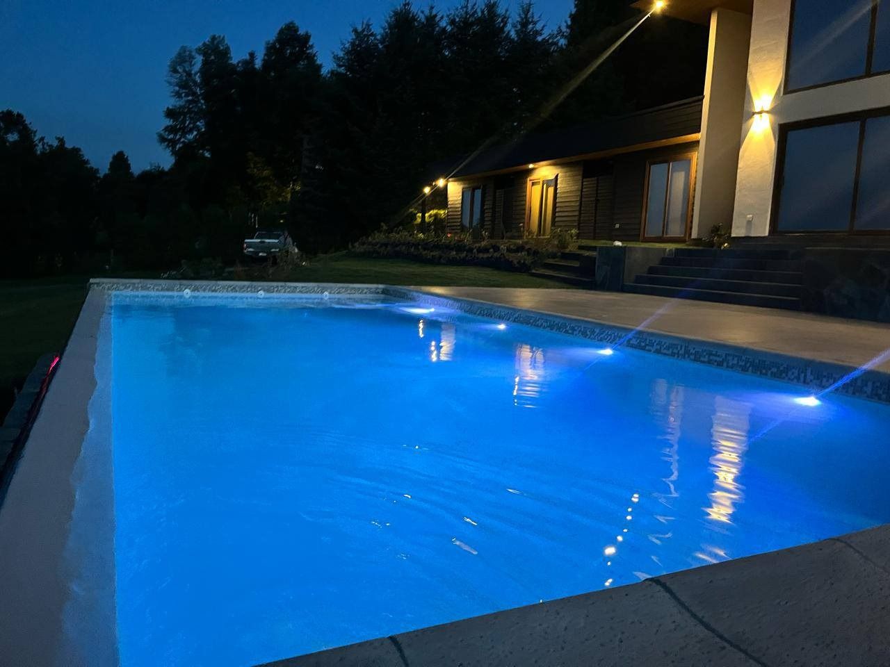 Piscina iluminada de noche con el agua cristalina